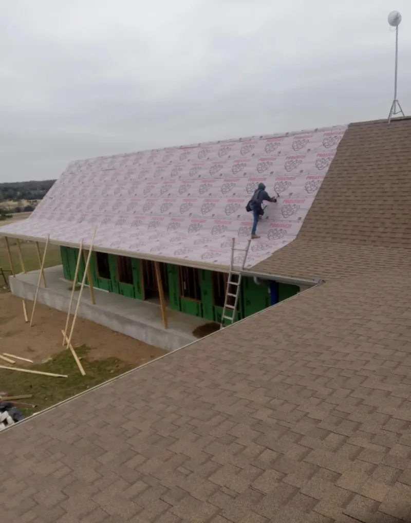 Worker preparing underlayment for a metal roof installation in Waverly